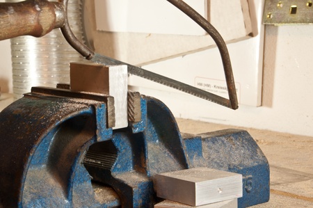Sawing in a block of metal in a vice on a wooden workbench