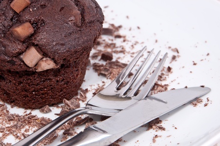 Brown muffins with pieces of chocolate and cutlery on a plateの写真素材