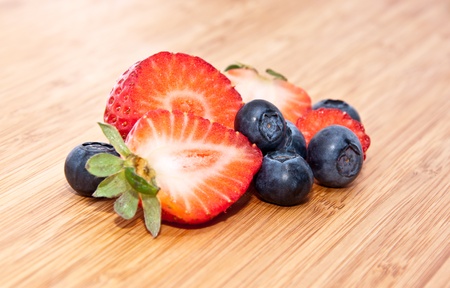 Heap of mixed berries (Strawberries and Blueberries) on a wooden backgroundの写真素材