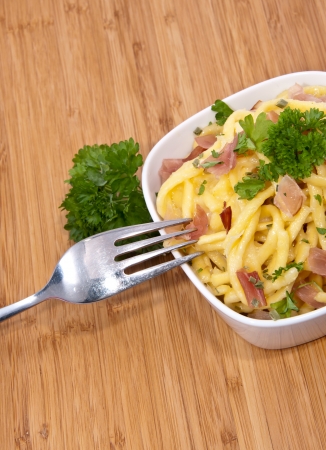 Bowl with Cheese Spaetzle and cutlery on wooden backgroundの写真素材