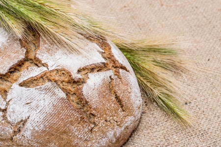 Loaf of bread with wheat on textile background