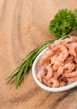 Small bowl with Shrimps and herbs on wooden backgroundの写真素材