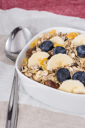 Muesli with fruits in a bowl on red tableclothの写真素材