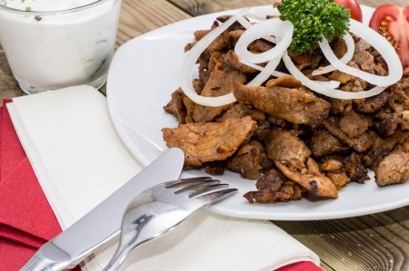 Kebab meat with Onions on a plate against wooden backgroundの写真素材