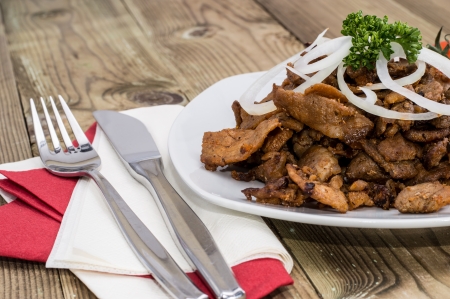 Kebab meat with Onions on a plate against wooden backgroundの写真素材