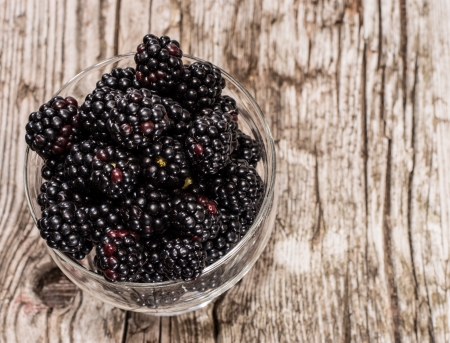 Fresh heap of Blackberries in a bowl on wooden backgroundの写真素材