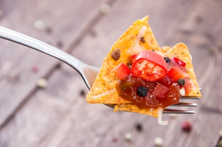 Nachos on a fork with sauce on wooden backgroundの写真素材