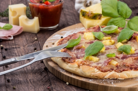 Fresh baked Pizza with Ham and Pineapples on wooden backgroundの写真素材