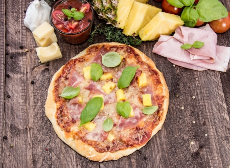 Fresh baked Pizza with Ham and Pineapples on wooden backgroundの写真素材