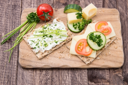 Crispbread with Cheese on a board against wooden backgroundの写真素材