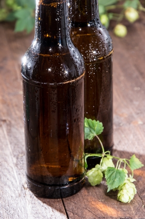 Two wet bottles of Beer decorated with Hops on wooden backgroundの写真素材