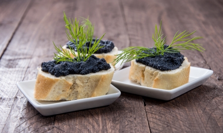 Some Caviar on fresh Baguette against wooden backgroundの写真素材