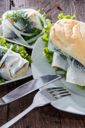 Fresh Herring with Onions on a baguette on wooden backgroundの写真素材