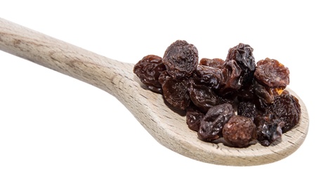 Raisins on a wooden spoon against white backgroundの写真素材