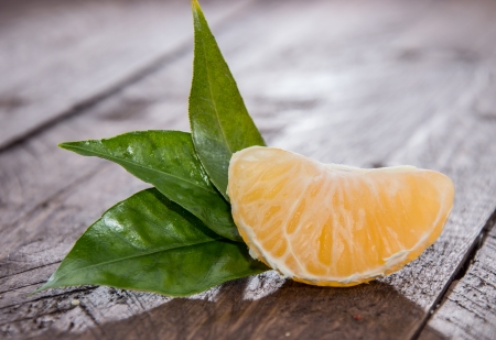Tangerine Pieces with leafs on wooden backgroundの写真素材