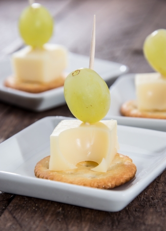 Pieces of Cheese on a Cracker topped with a Grapeの写真素材
