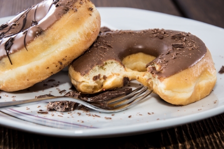 Chocolate Donuts on a plate on wooden backgroundの写真素材