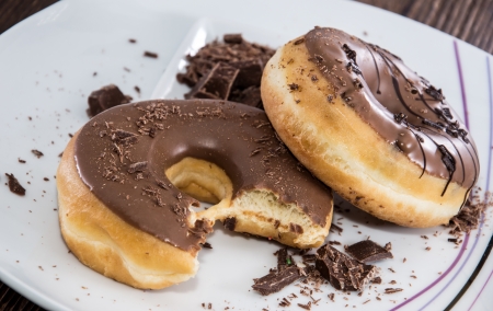 Chocolate Donuts on a plate on wooden backgroundの写真素材