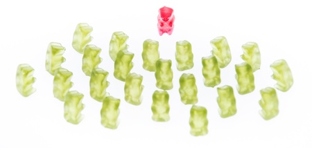 Red Gummi Bear in front of green Gummi Bears (isolated on white)の写真素材