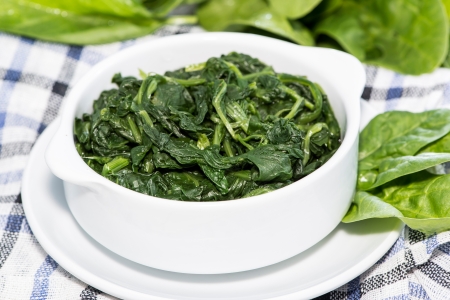 Bowl with fresh cooked Spinach on wooden backgroundの写真素材