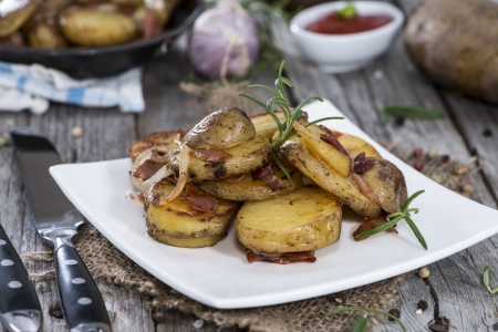Portion of roasted Potatoes with bacon and fresh herbsの写真素材