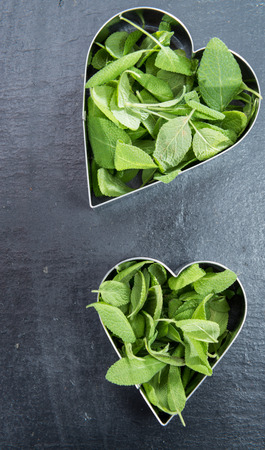 fresh Herbs in heart shaped bowl on dark backgroundの写真素材