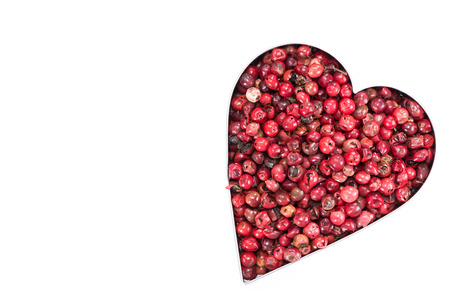 Pink Peppercorns in a Heart Shape isolated on pure whiteの写真素材