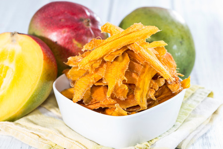 Small bowl with dried Mango slices and some fresh fruitsの写真素材