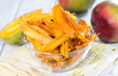 Small bowl with dried Mango slices and some fresh fruitsの写真素材