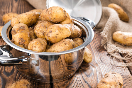 Heap of freh Potatoes on wooden background (close-up shot)の写真素材