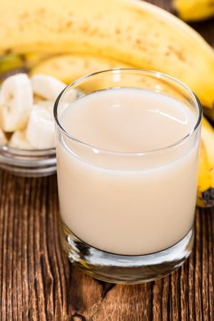 Banana Juice in a glass with fresh fruits (on wooden background)の写真素材