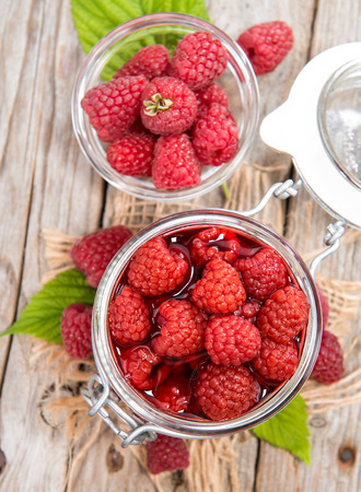 Preserved Raspberries in a glass with some fresh fruits