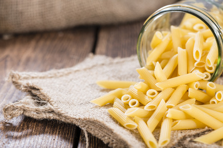 Portion of uncooked Penne on rustic wooden backgroundの写真素材