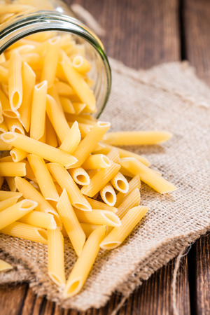 Uncooked Penne (detailed close-up shot) on rustic wooden backgroundの写真素材
