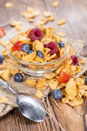 Cornflakes with fresh Strawberries, Raspberries and Blueberries on wooden backgroundの写真素材