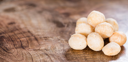 Roasted and salted Macadamia nuts on rustic wooden backgroundの写真素材