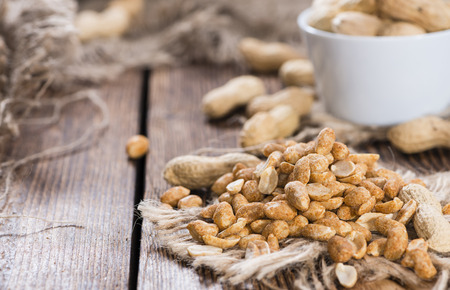 Heap of Peanuts (roasted and salted) on dark wooden background