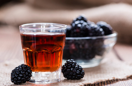 Blackberry Liqueur in a shot glass (on rustic wooden background)の写真素材