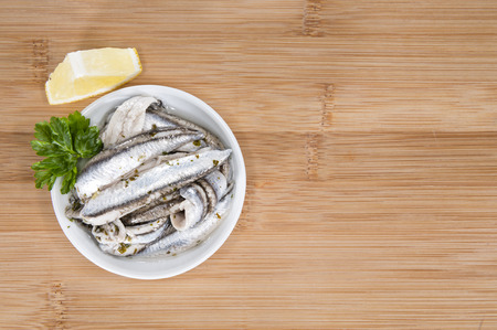 Pickled Anchovis with herbs (close-up shot) on wooden backgroundの写真素材