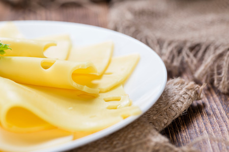 Sliced Cheese (close-up shot) on vintage wooden background