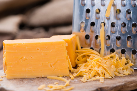 Portion of grated Cheddar Cheese on rustic wooden backgroundの写真素材