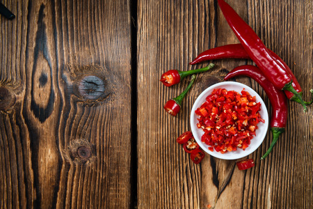 Cutted red Chilis in a bowl (close-up shot) on wooden backgroundの写真素材