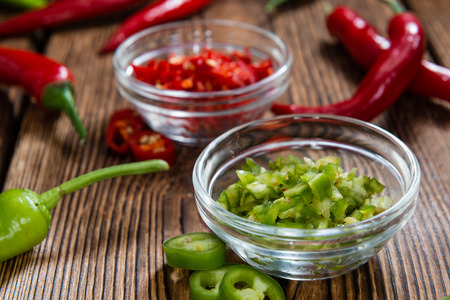 Red and Green Chilis (cutted) on wooden backgroundの写真素材