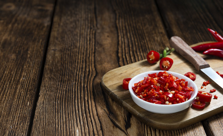 Red Chilis (cutted) on vintage wooden backgroundの写真素材