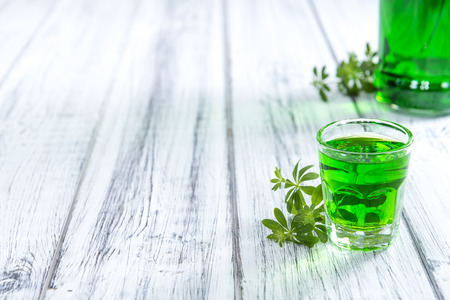 Woodruff Liqueur in a small glass (on wooden background) Woodruff Liqueur in a small glass (on wooden background)