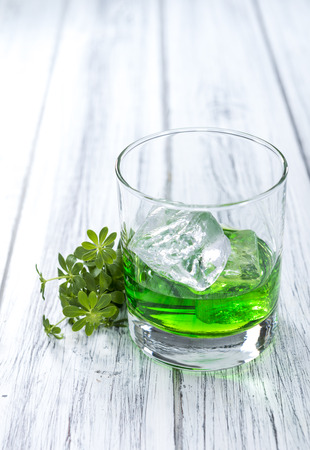 Woodruff Liqueur in a small glass (on wooden background) Woodruff Liqueur in a small glass (on wooden background)