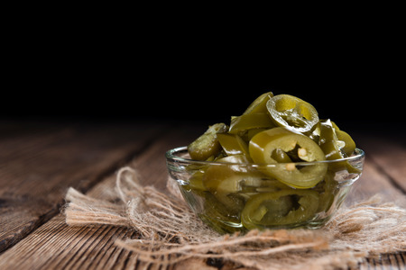 Sliced Japalenos (preserved) on rustic wooden backgroundの写真素材