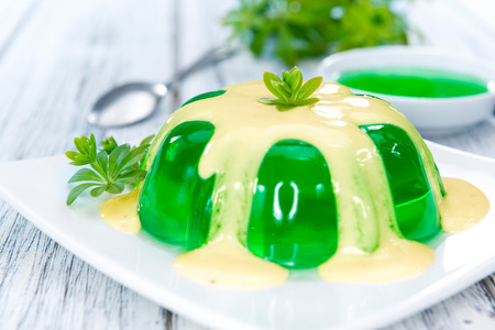Portion of Woodruff Jelly with Vanilla Sauce on bright wooden background