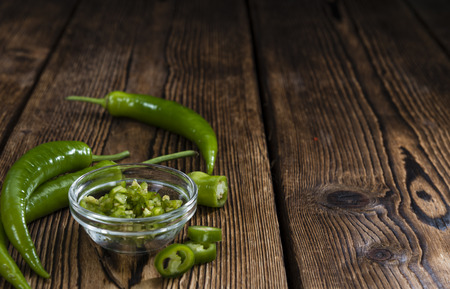 Green Chilis (cutted) on an old rustic wooden tableの写真素材