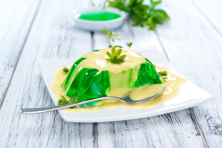 Woodruff Jelly with Vanilla Sauce on wooden background